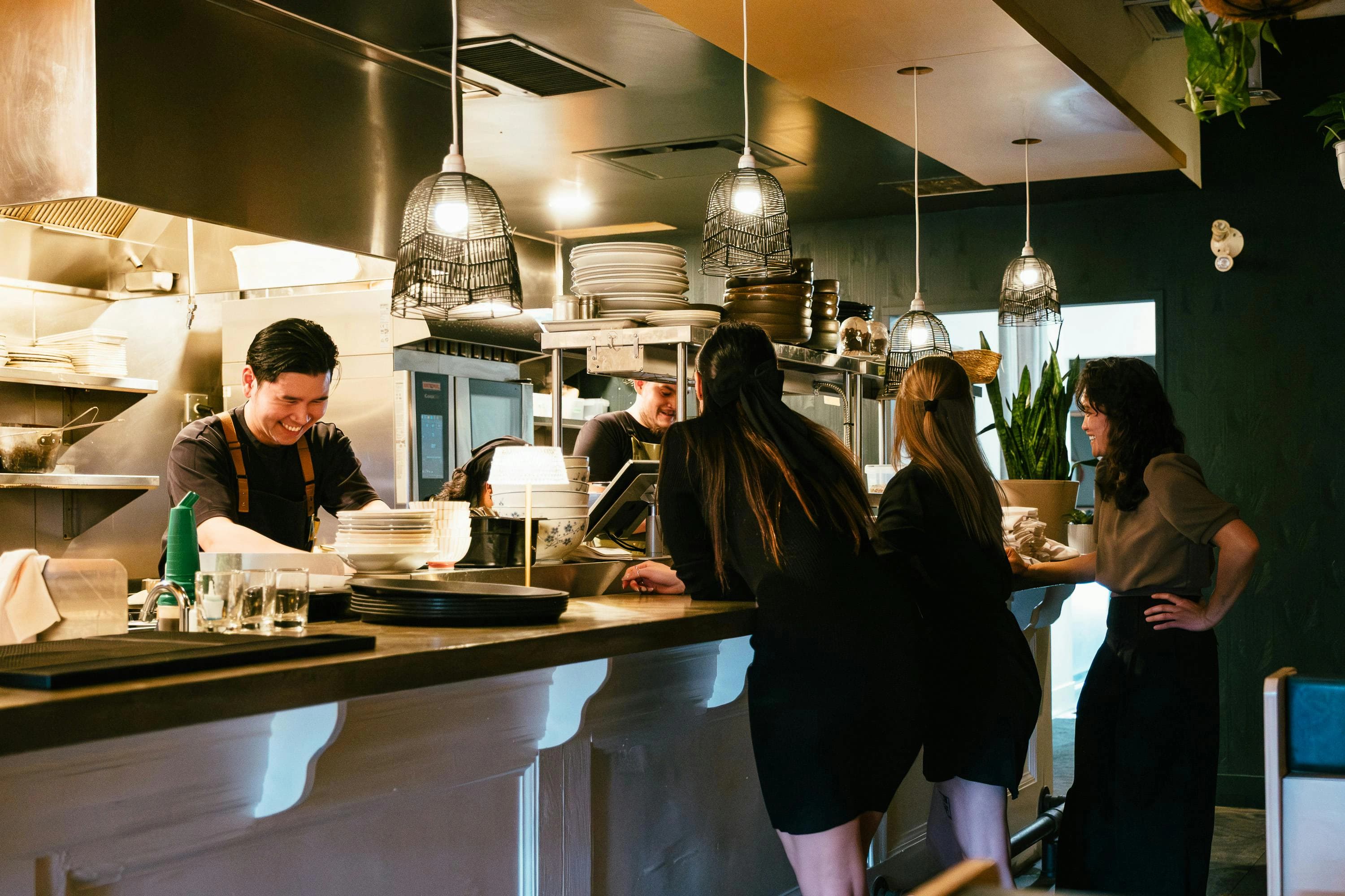 Busy restaurant service counter during a high-pressure shift with staff and guests in view